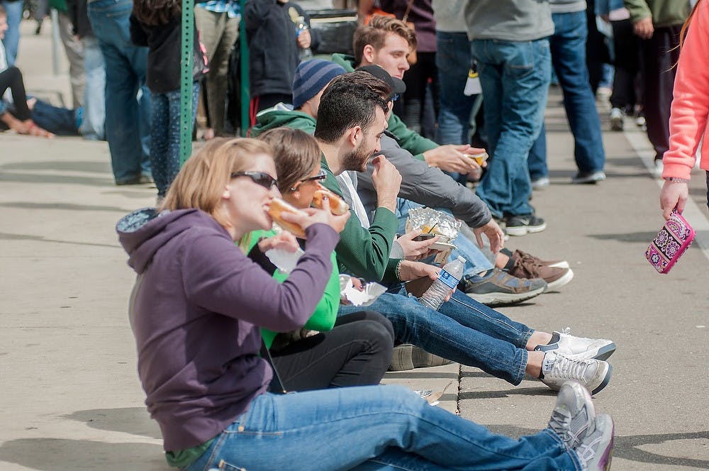 <p>People eat food while sitting on a curb April 25, 2015, on Albert Ave. during Taste of East Lansing. The event featured various live musical performances, food from restaurants in the area, and children's activities. Allyson Telgenhof/The State News.</p>