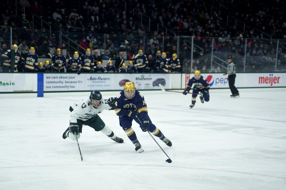 <p>Notre Dame junior Jesse Lansdell moving the puck forward as Michigan State sophomore Kristof Papp tries to stop him on Feb. 18, 2022. Spartans lost 2-1 against Notre Dame.<br/><br/><br/><br/></p>