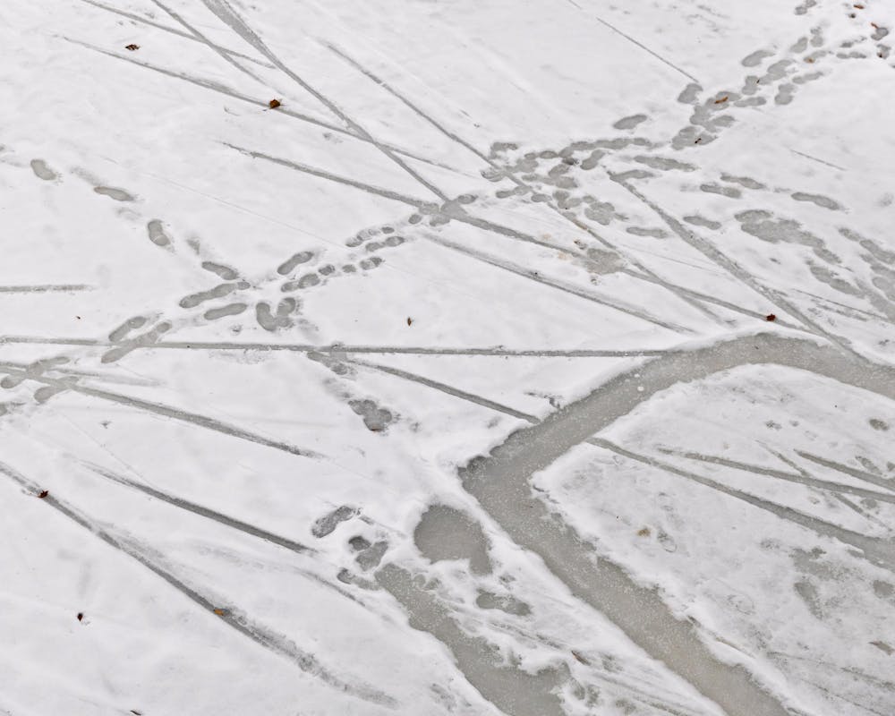 The iced over Red Cedar River has many footprints in it as MSU students walked over it in East Lansing, MI on Feb. 11, 2026.