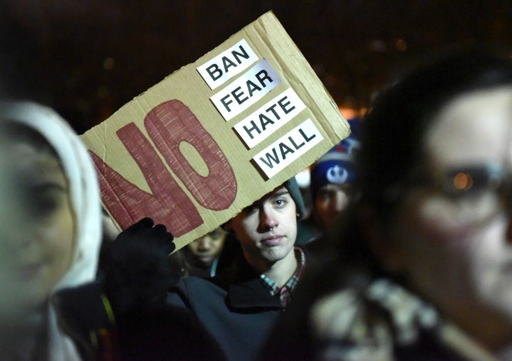 James Madison freshman Jonathan Walkotten raises his sign on Jan. 31, 2017 at The Rock. The Michigan State Muslim Students' Association hosted a "No Ban, No Wall: Spartans for Sanctuary and Solidarity" as a response to President Trump's executive order on Muslim immigrants and refugees.