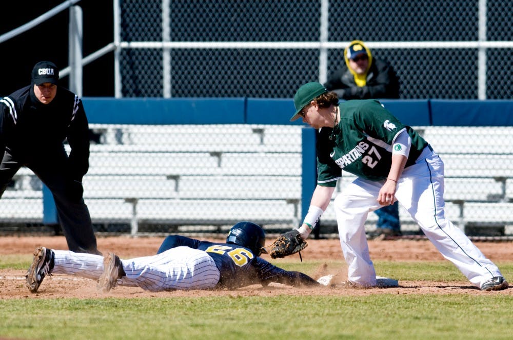 Senior first baseman Jeff Holm attempts to tag Michigan outfielder Patrick Biondi Sunday at Ray Fisher Stadium at Wilpon Baseball Complex in Ann Arbor. The Spartans defeated the Wolverines, 5-4, in game one of a double header. Matt Radick/The State News