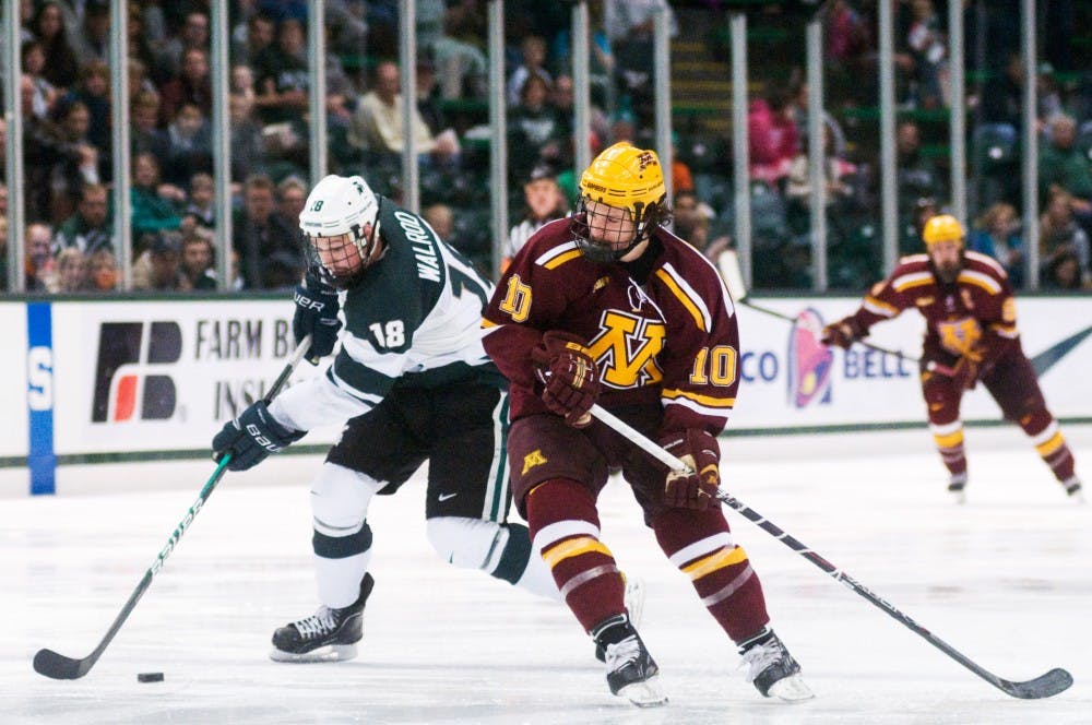 Junior forward Kevin Walrod skates past Minnesota defender Ben Marshall Friday evening at Munn Ice Arena. The Spartans defeated the Golden Gophers 4-3. Matt Radick/The State News
