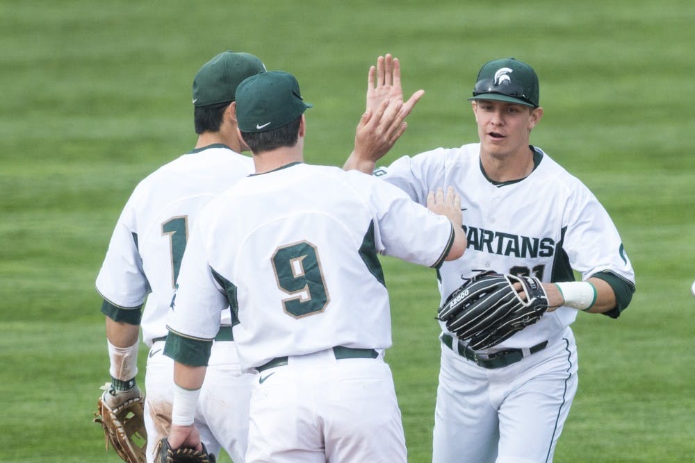 Sophomore outfielder Dan Chmielewski (21) goes to high five freshman outfielder Danny Gleaves (1) and senior infielder Dan Durkin (9) after winning the game against Ohio State on April 14, 2017 at McLane Baseball Stadium at Kobs Field. The Spartans defeated the Buckeyes, 2-0.