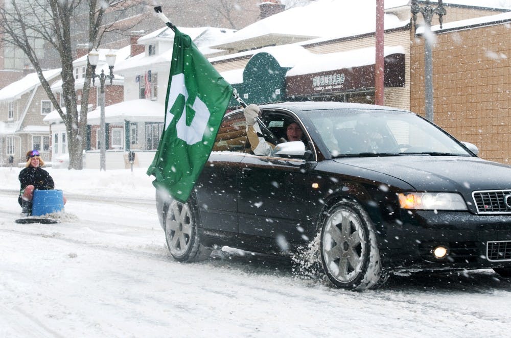 	<p>Students drive down Albert Ave. waving a Michigan State flag and pulling their friend on a sled celebrating the snow day on Wednesday morning. Classes were canceled on Feb. 2 for the first time since 1994 because of a winter storm.</p>