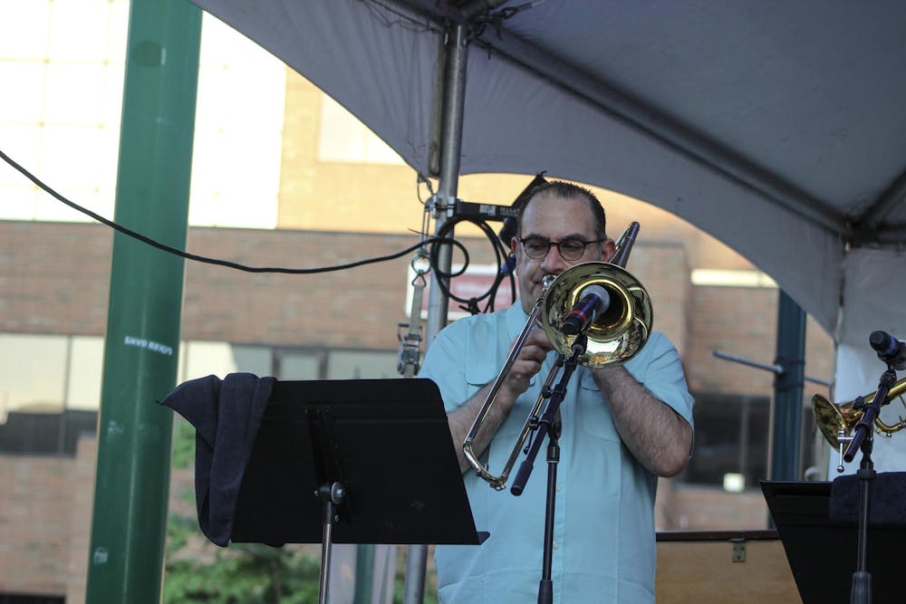 A trombone player warms up to play with his band, Aguanko, at the East Lansing Summer Solstice Jazz Festival on June 21, 2024. 