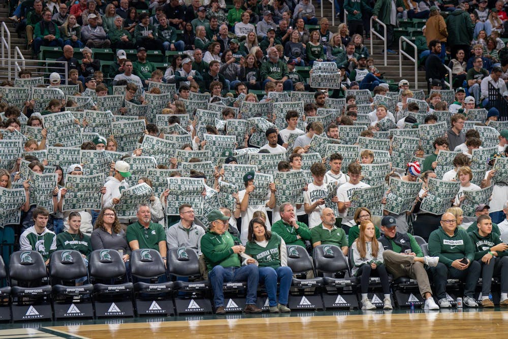 Michigan State fans take part in the tradition of pretending to read a Michigan State newspaper as Detroit Mercy introduces its starting lineup at Breslin Center in East Lansing, Mich., on Friday, Nov. 21, 2025.