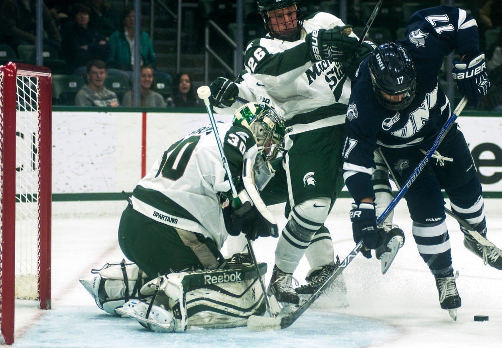 <p>New Hampshire forward Marcus Vela looks to protect the puck as senior goaltender Jake Hildebrand guards the net during the first period of the game against New Hampshire on Nov. 7, 2015, at Munn Ice Arena. The Spartans defeated the Wildcats, 7-4. </p>