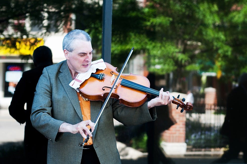 <p>Lansing resident Gary Butterwick plays his viola June 3, 2014, in Washington Square in Lansing. Gary has been playing viola for five years. This was his first time busking with his viola in Lansing. Corey Damocles/The State News</p>