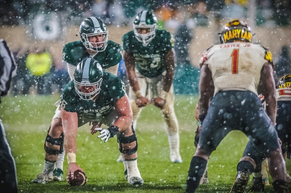 Senior offensive lineman Brian Allen (65) prepares to snap the ball to sophomore quarterback Brian Lewerke (14) during the game against Maryland on Nov. 18, 2017, at Spartan Stadium. The Spartans defeated the Terrapins, 17-7.