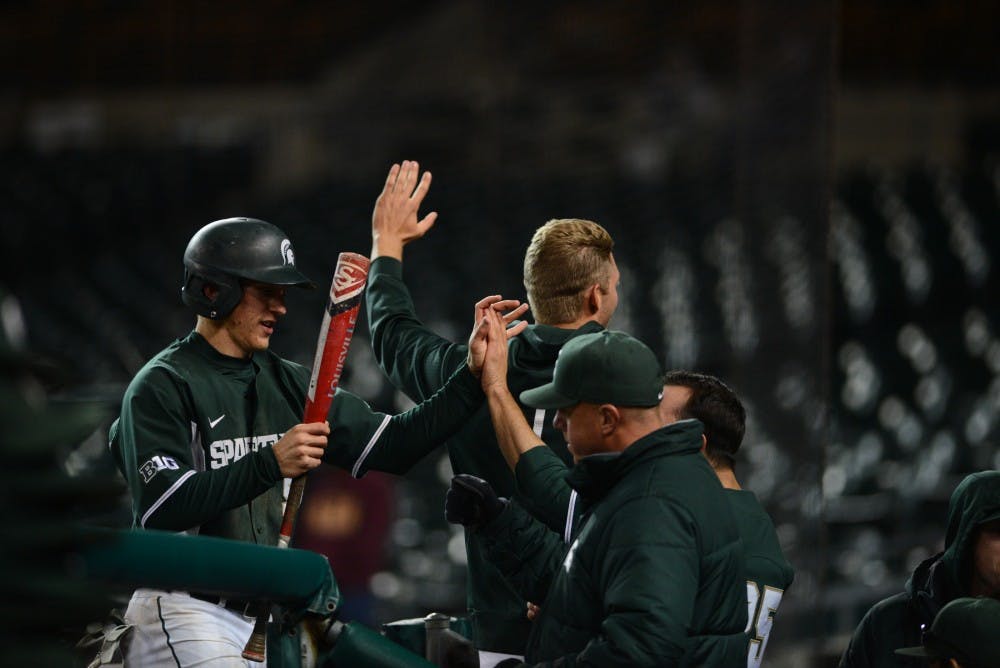 Junior infielder Jordan Zimmerman high fives head coach Jake Boss Jr. after scoring a run during the game against Central Michigan on April 14, 2016 at Comerica Park in Detroit. The Spartans defeated the Chippewas, 7-3. 