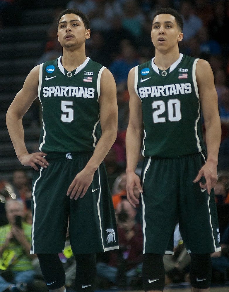 <p>Junior guard Bryn Forbes and senior guard Travis Trice watch a free-throw Mar. 22, 2015, during the game against Virginia in the Round of 32 of the NCAA tournament at the Time Warner Cable Arena in Charlotte, NC. The Spartans defeated the Cavaliers 60-54.  Alice Kole/The State News</p>