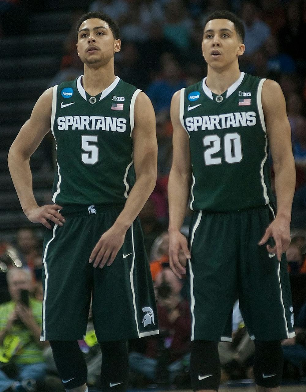 <p>Junior guard Bryn Forbes and senior guard Travis Trice watch a free-throw Mar. 22, 2015, during the game against Virginia in the Round of 32 of the NCAA tournament at the Time Warner Cable Arena in Charlotte, NC. The Spartans defeated the Cavaliers 60-54.  Alice Kole/The State News</p>