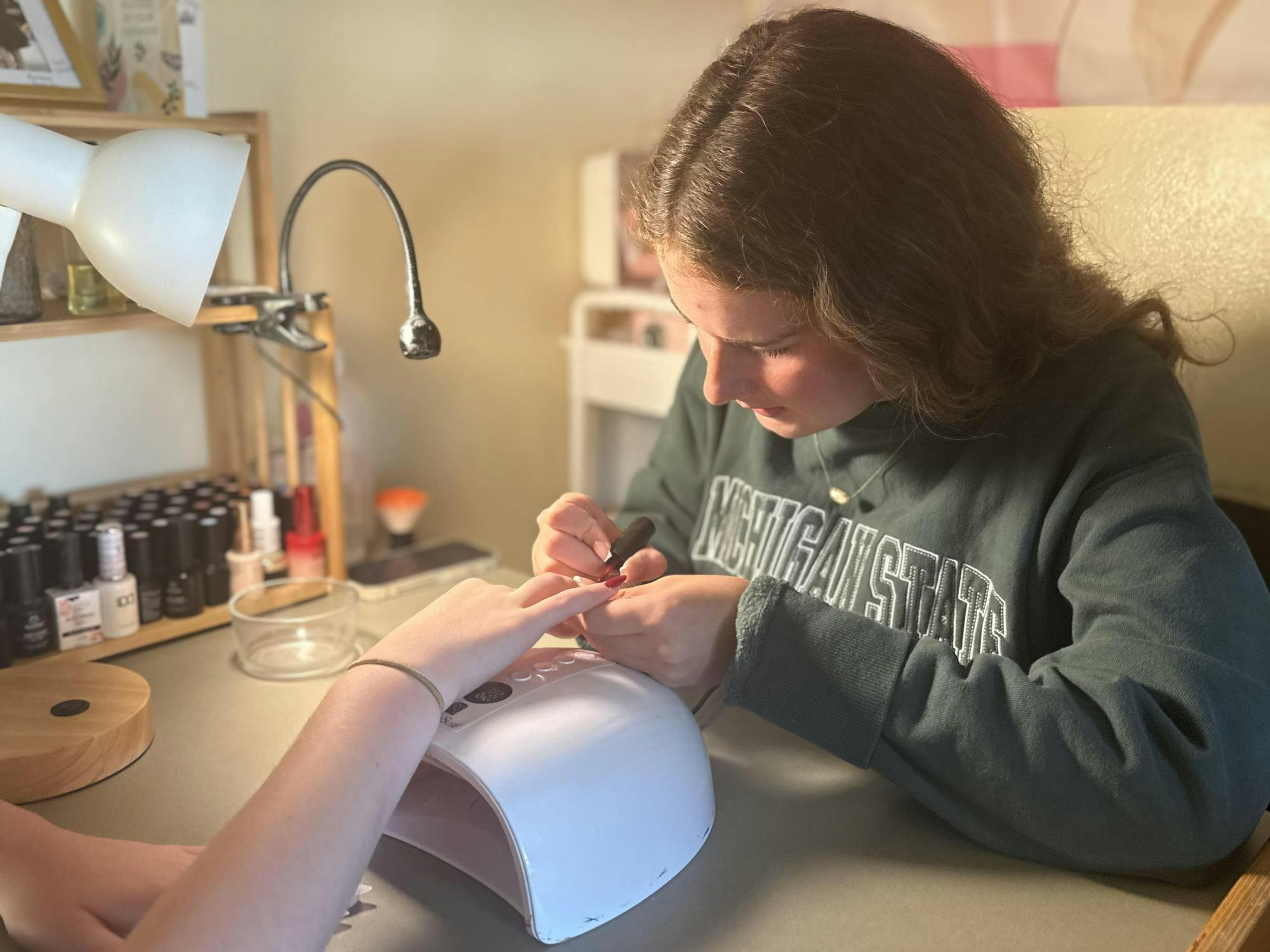 <p>Avery Lampen, exploratory studies freshman and nail tech, paints Makenna Hartley, communicative science and disorders freshman, nails in North Hubbard Hall on Sunday, Sept. 27, 2026. </p>