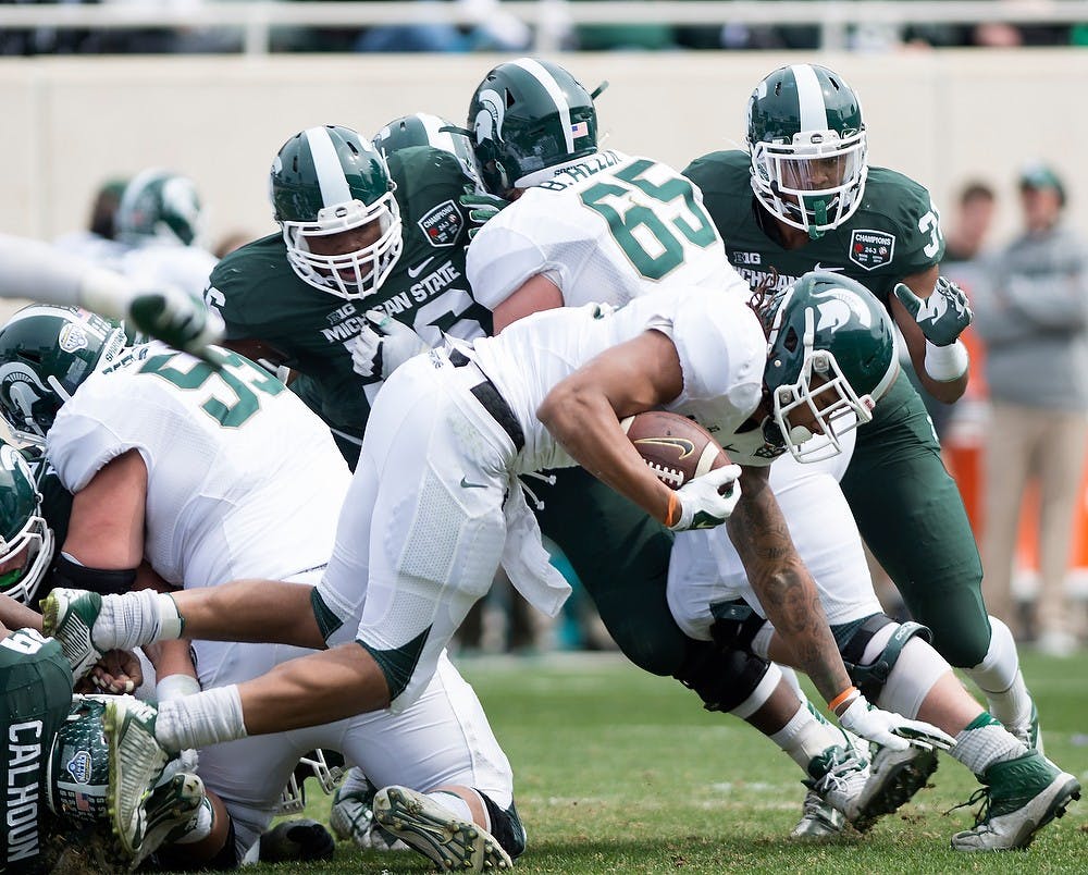 <p>Sophomore running back Gerald Holmes is tackled April 25, 2015, during the Green and White Spring Game at Spartan Stadium. The white team defeated the green team, 9-3. Erin Hampton/The State News</p>