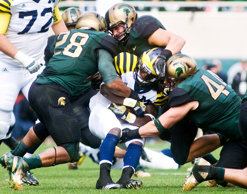 The Spartans wrap up Michigan running back Vincent Smith Saturday at Spartan Stadium. The Spartans defeated the Wolverines 28-14. Matt Radick/The State News