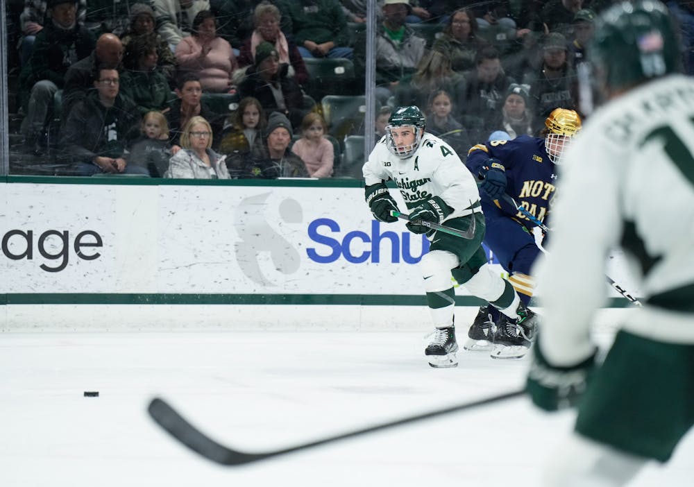 <p>Junior defender Nash Nienhuis (4) goes after the puck during a game at Munn Ice Arena on Feb. 3, 2023. The Spartans defeated the Fighting Irish 3-0.</p>