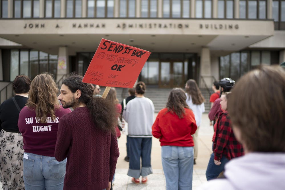 Attendees hold protest signs while gathered during the Stand Up for Higher Education Rally outside the Hannah Administration Building on April 17, 2025.