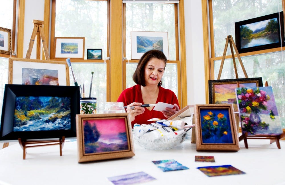 Surrounded by her paintings, East Lansing resident Juanita Baldwin works on a small peice for the East Lansing Art Expo. The show, presented by the Public Art Gallery in collaboration with the City of East Lansing, features many community artists and opens January 22. Matt Hallowell/The State News