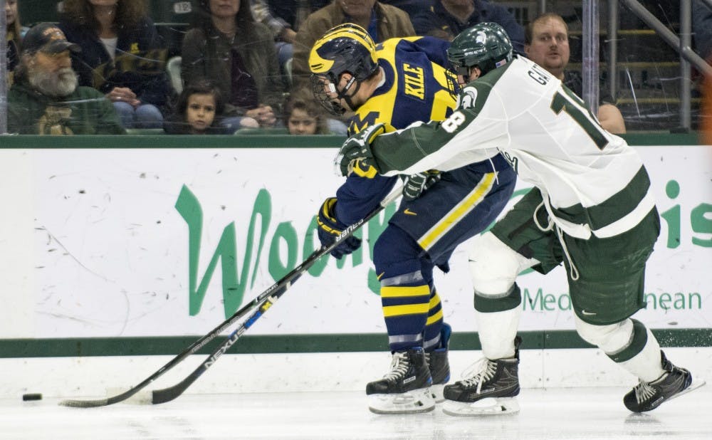 Michigan forward Alex Kile (23) attempts to gain control of the puck as he is defended by junior defense Carson Gatt (18) during the second period of the game against Michigan on Jan. 21, 2017 at Munn Ice Arena. The Spartans were defeated by Wolverines, 2-3.