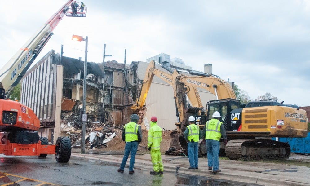 <p>Several workers survey the area during the demolition of the blighted building on Oct. 7, 2017, at the corner of Grand River and Abbot. Two lanes on Grand River in front of the building and part of Abbot were closed for safety.</p>