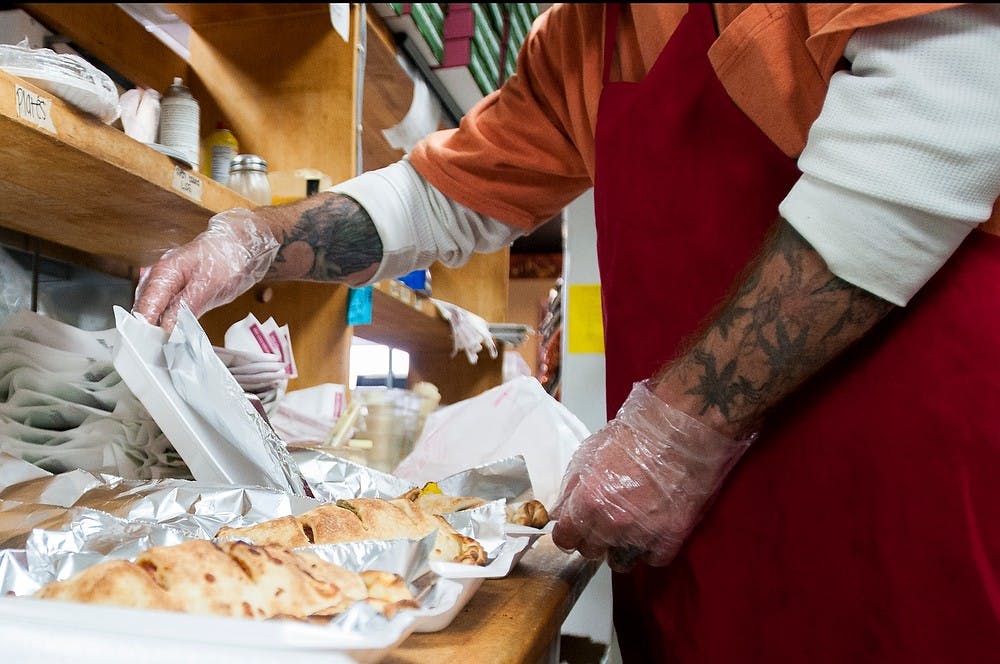 <p>Lansing resident Casey McCartney prepares a line of calzones to go on Nov. 12, 2014, at Mancino's Italian Eatery. Dylan Vowell/The State News</p>