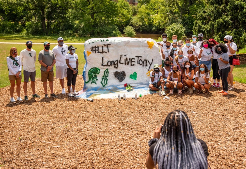 The MSU Track and Field team poses for a photo at the memorial for long jumper Tony Martin at the Rock on Farm Lane July 20, 2020. Martin died in a shooting in his hometown of Saginaw the morning of July 19. Martin held the high school state record for the long jump, with a jump of 26 feet and six inches.