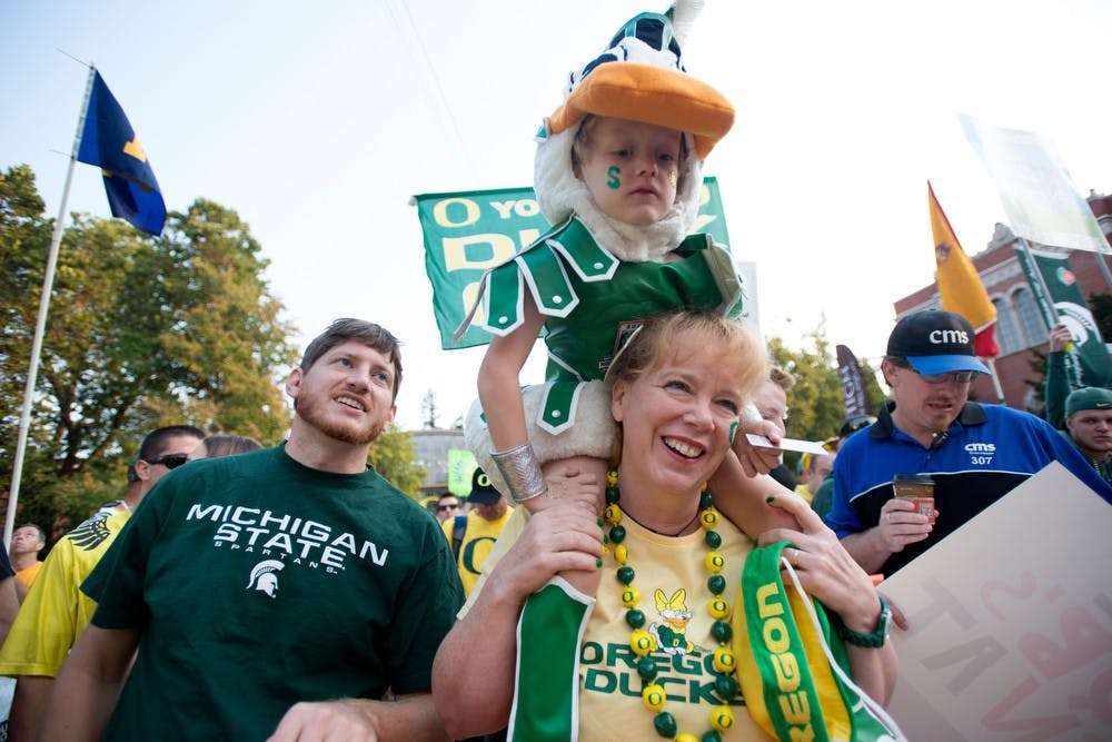 <p>Tampa, Fla., resident Kazimer Machuga, 5, rests on his mom&#8217;s shoulders, Kim McCormick, as his father James Machuga watches during <span class="caps">ESPN</span>&#8217;s College GameDay on Sept. 6, 2014, near the corner of Kincaid Street and 13th Ave on the edge of University of Oregon&#8217;s campus in Eugene, Ore. Kazimer sported a duck costume in a Spartan outfit to show love for both teams. Julia Nagy/The State News</p>