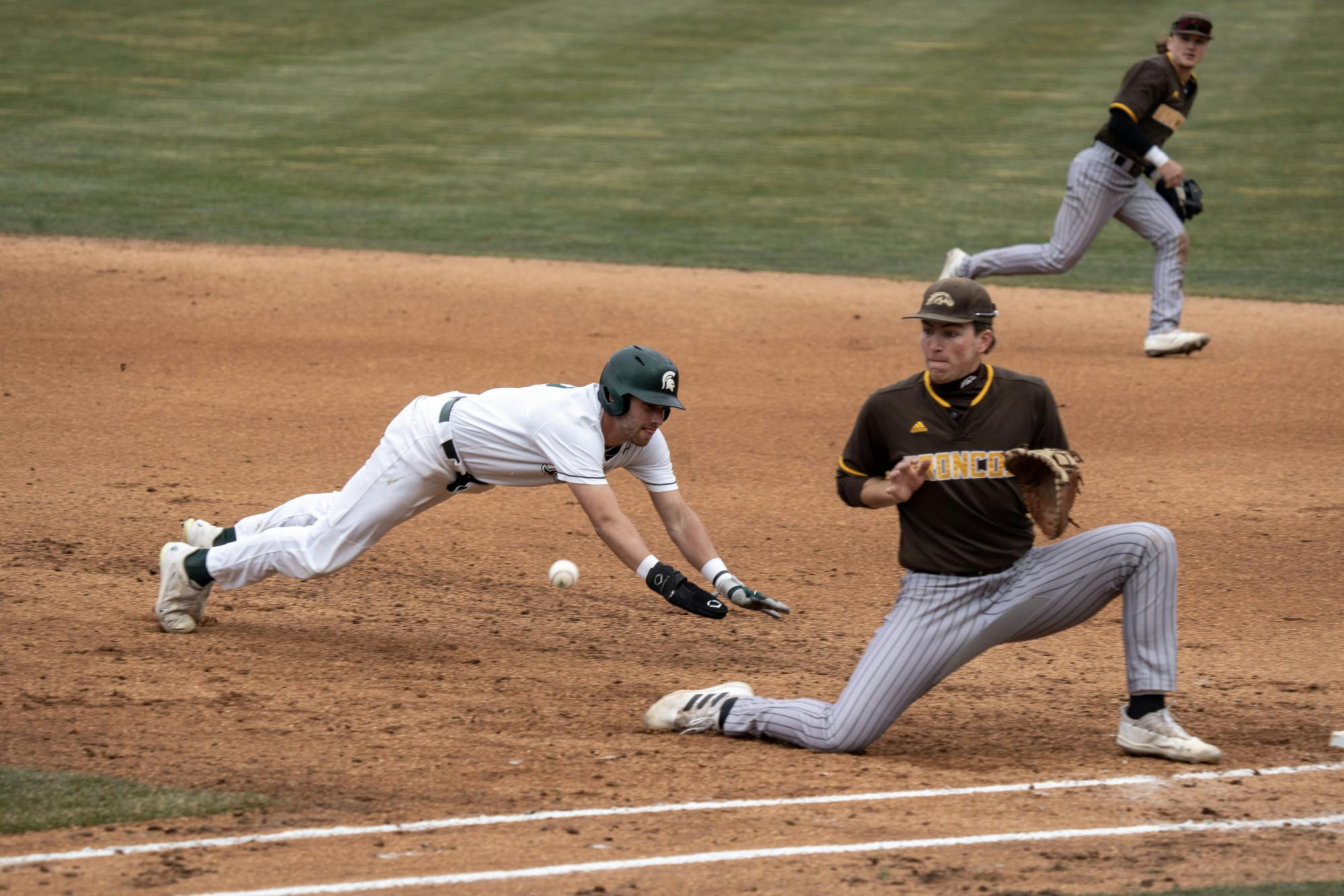 <p>Junior Dillon Kark dives headfirst back to first base, beating the pickoff attempt by Western Michigan. The Spartans would go on to win their home opener 8-3 on March 22, 2023</p>