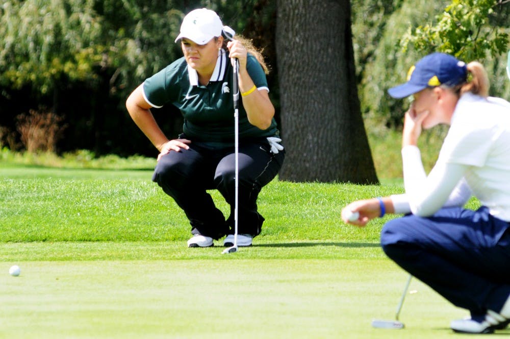 Sophomore Liz Nagel inspects the putting green with Michigan Devon Compton at Forest Akers West Golf Course Sunday afternoon. The Spartans won the Fossum Invitational held over the weekend. Justin Wan/The State News