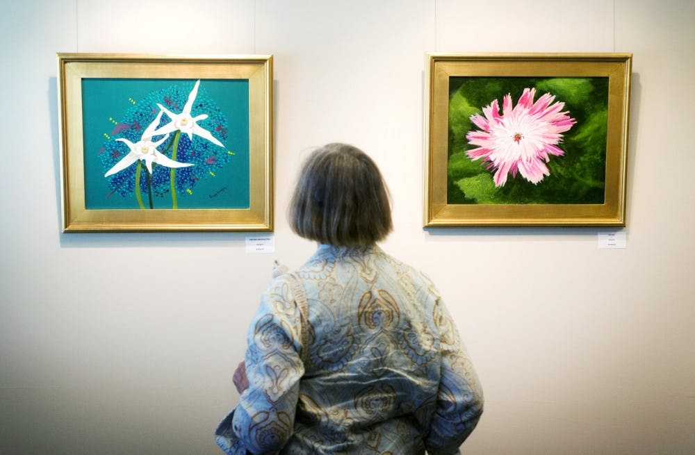 	<p>East Lansing resident Rosemarie Turke admires the work of Peggy Lovejoy at her gallery&#8217;s opening on Sunday at the East Lansing Hannah Community Center located at 819 Abbot Rd. &#8220;My retirement period inspired me to begin art lessons on a whim, and I quickly found not only a passion for it, but an easy way to lose myself and cure all kinds of moods and ills of the heart,&#8221; Lovejoy said of her art. Mo Hnatiuk/The State News</p>