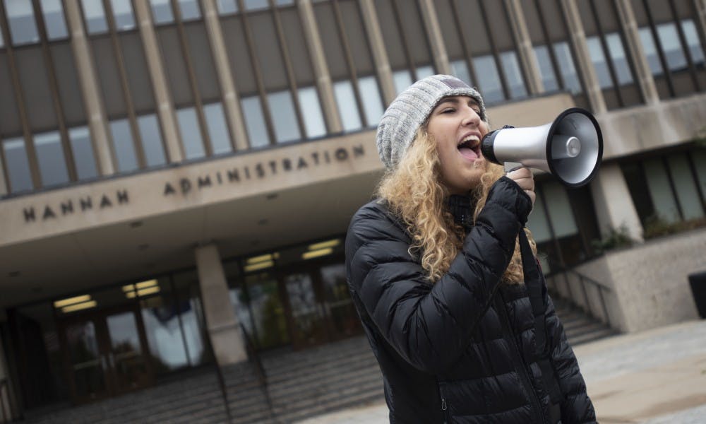 <p>Makenna Carpenter, supply chain management junior, chants in front of the Hannah Administration Building on Oct. 27. Carpenter said that every hate crime that has happened on Michigan State's campus is wrong and "dealing with these types of instances is what Michigan State needs to work on."</p>
