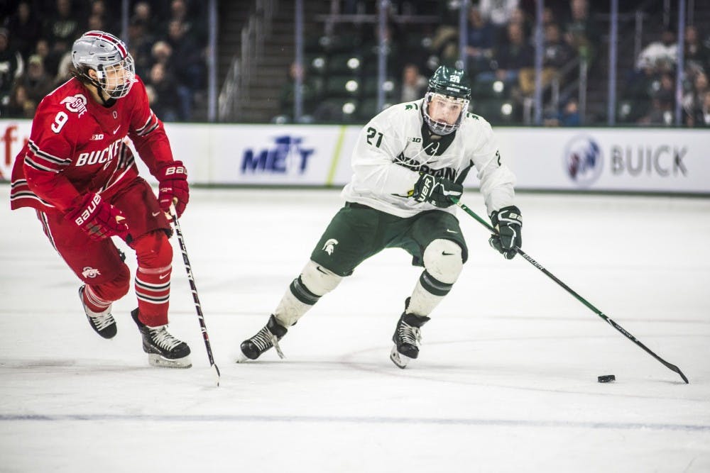 Freshman left wing Jake Smith (21) drives the puck up the rink during the men's hockey game against Ohio State on Jan. 5, 2018 at the Munn Ice Arena. The Spartans were defeated by the Buckeyes, 4-1. (Nic Antaya | The State News)