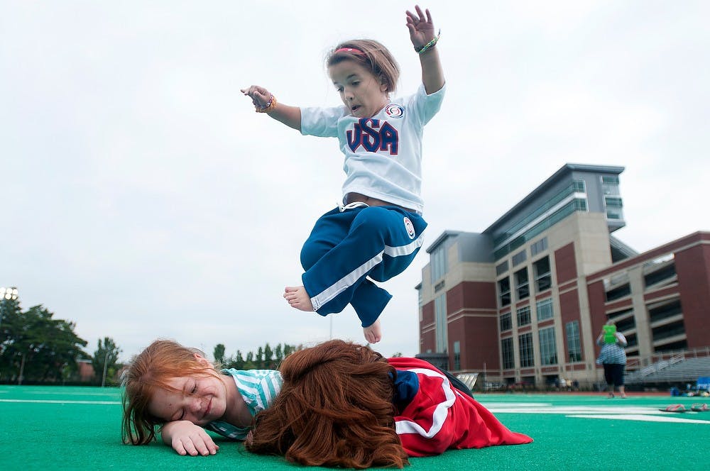 	<p>Pittsburgh resident Katherine Valli, 10, jumps over Timonium, Md., residents Angie, 11, right, and Megan Gioffreda, 6, on Aug. 6, 2013, at Ralph Young Stadium during the World Dwarf Games. The three were playing on the field after the flag football event. Julia Nagy/The State News</p>
