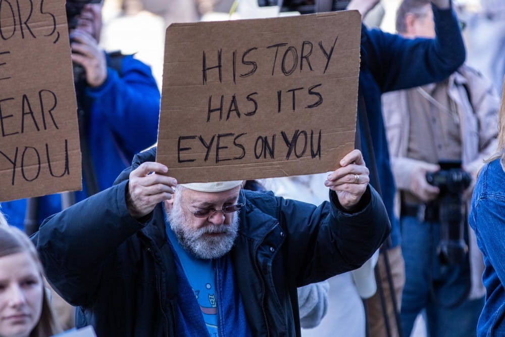 A man holds up a sign at the Rally for Resignations outside the Hannah Adminstration Building on April 20, 2018. The event had a number of speakers including Morgan McCaul and Kaylee Lorincz, both survivors of assualt by Larry Nassar.