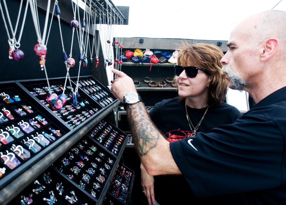 	<p>DeWitt residents Bill and Heather Frarey admire the jewelry created by artist Matt Cole Sunday afternoon at the 48t Annual East Lansing Art Festival. Cole takes old bowling balls and recycles them into jewelry he then sells. </p>