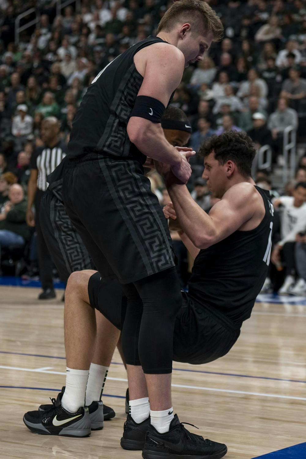 <p>Michigan State junior forward Jaxon Kohler (0) helps senior center Szymon Zapala (10) up after falling at Little Caesars Arena in Detroit on Dec. 17, 2024.</p>