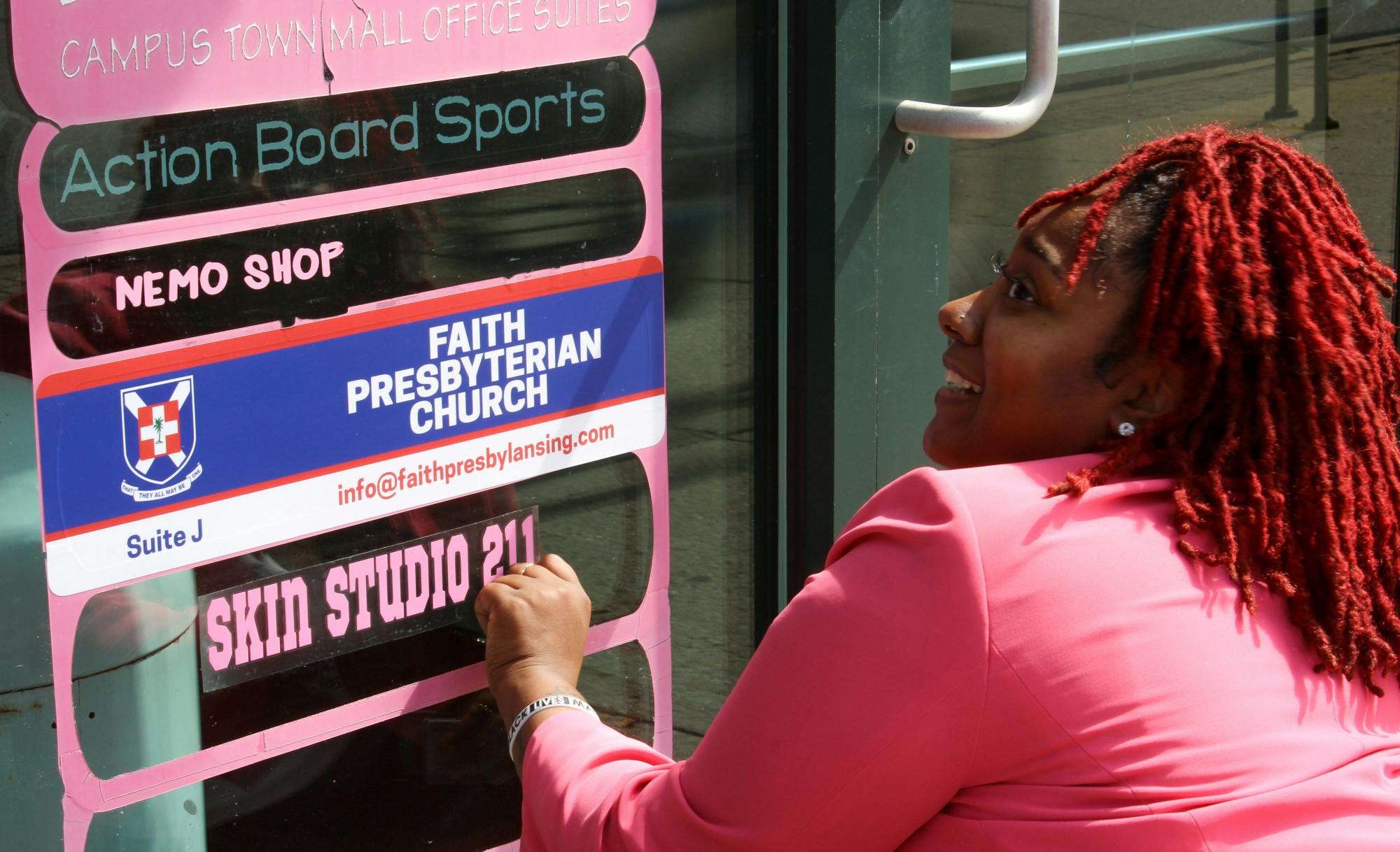 Lorin Cumberbatch, owner of Skin Studios, applies a decal to the Campus Town Mall building. Cumberbatch's grand opening is August 29. 