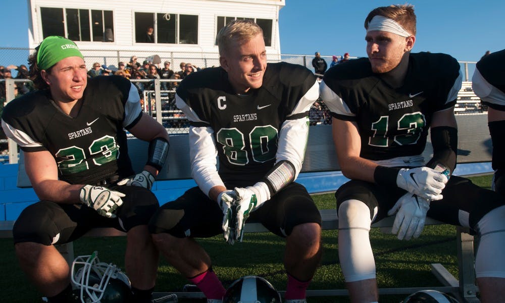 <p>From left to right, sophomore running back Zach Greene, senior wide receiver Jake Sterling and junior wide receiver Alec Papes watch the game from the bench during the MSU Club Football game against Wright State University on Oct. 25, 2015 at Hope Sports Complex, 5801 North Aurelius Road, in Lansing. The team began just a year ago and has been undefeated this season. </p>