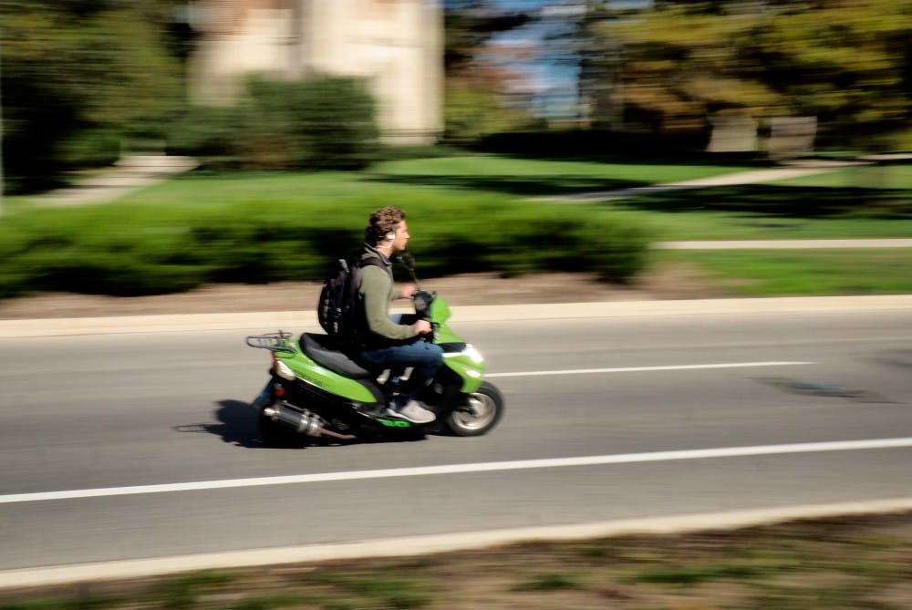 <p>An MSU student drives a moped in front of the MSU Library on October 23, 2019. </p>