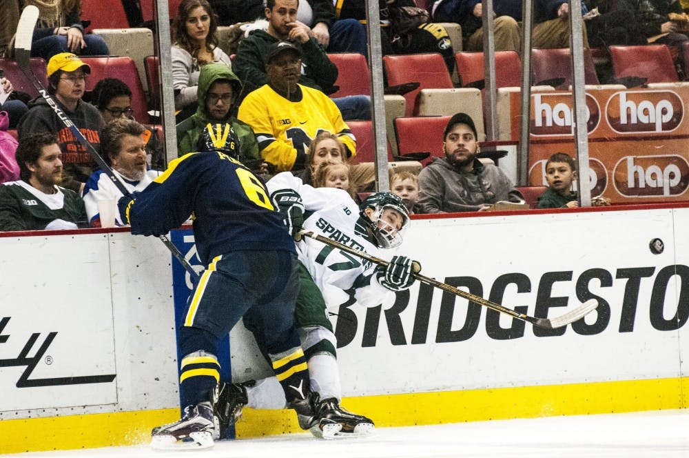 Freshman wingman Taro Hirose (17) flicks the puck and is hit by Michigan defenseman Sam Piazza (6) during the second period of the 52nd Annual Great Lakes Invitational third-place game against the University of Michigan on Dec. 30, 2016 at Joe Louis Arena in Detroit. The Spartans were defeated by the Wolverines in overtime, 5-4.