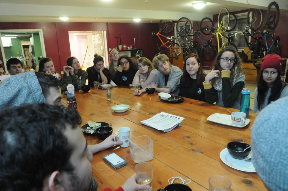 Students sit around and eat a meal during the Phoenix House co-op family dinner on Feb. 14, 2016 at the Phoenix Cooperative House on 239 Oakhill Avenue in East Lansing. 