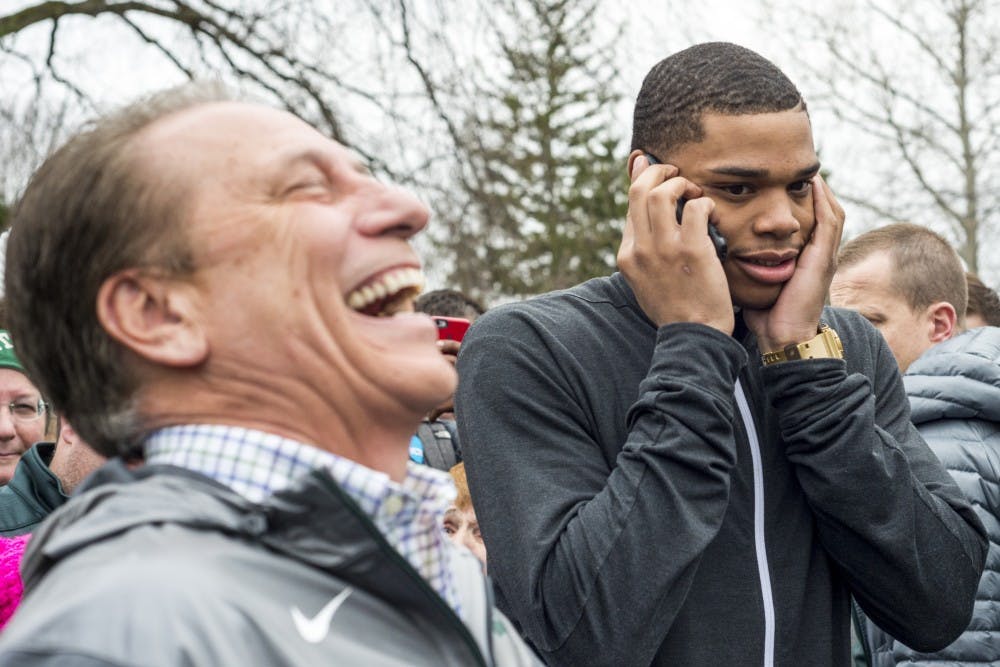 Freshman forward Miles Bridges (22), right, talks on the phone with a family member as head coach Tom Izzo laughs before Bridges's announcement that he will be continuing his MSU basketball career in the 2017-2018 season on April 13, 2017 at The Spartan statue. Hundreds of students gathered around the statue in support of Miles Bridges's return to MSU.