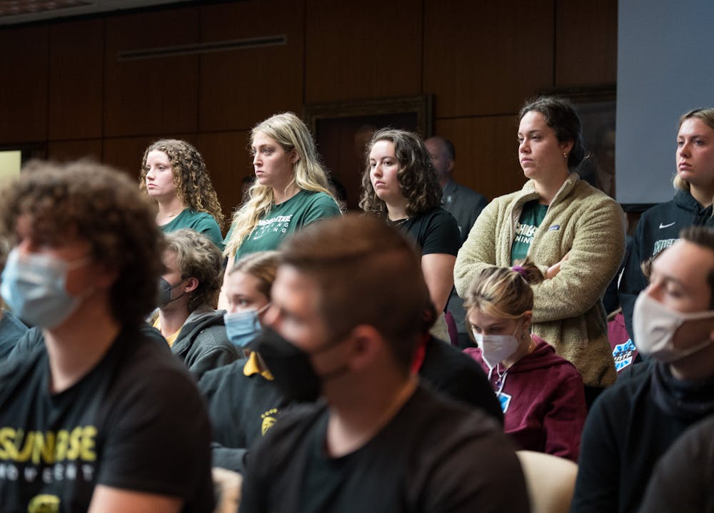 The Michigan State University Board of Trustees met in the Hannah Administration Building on April 22, 2022. Supporters of the reinstatement of the varsity swim and dive team stand during their peer's public comment. 