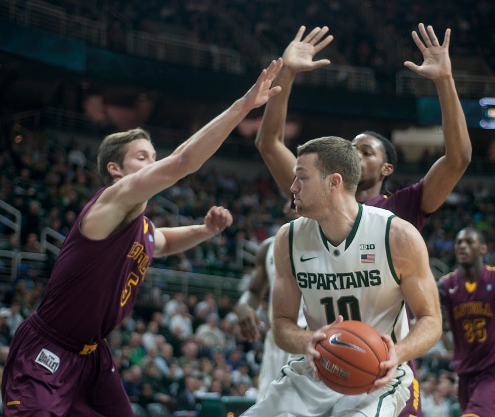 <p>Junior forward Matt Costello tries to pass the ball past Loyal guard Joe Crisman, 5, and forward Montel James, 24, to attempt a layup Nov. 21, 2014, at Breslin Center. The Spartans defeated the Ramblers, 87-52. Costello scored a total of 13 points and recovered 11 rebounds. Raymond Williams/The State News</p>
