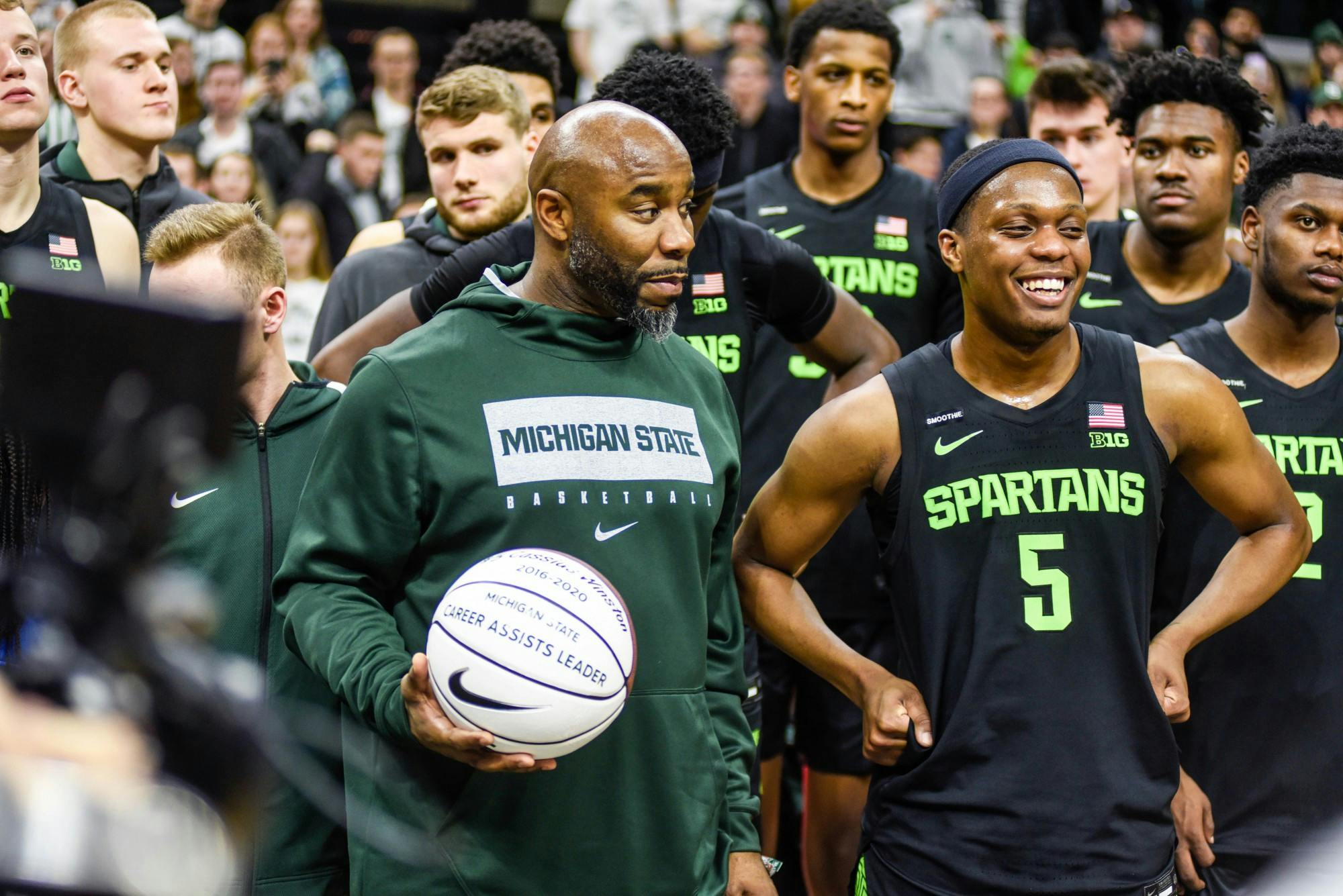 Former MSU basketball player Mateen Cleaves, left, and senior guard Cassius Winston (5), right, stand together as Cassis is recognized for having the most assists in his career at 817 during the game against Wisconsin at Breslin Center on Jan. 17, 2020.The Spartans defeated the Badgers, 55-67.