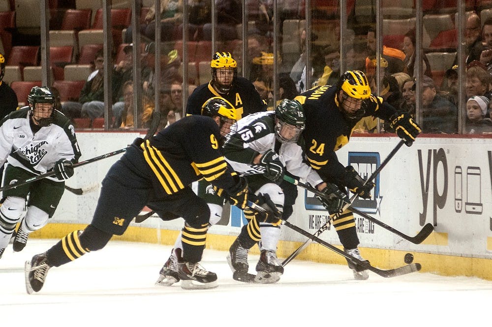 <p>Then-sophomore forward Mackenzie MacEachern races then-Michigan defensemen Michael Downing and Kevin Lohan to the puck March 20, 2015, during the Big Ten Hockey Tournament at Joe Louis Arena. The Spartans lost to the Wolverines, 4-1. Allyson Telgenhof/The State News.</p>
