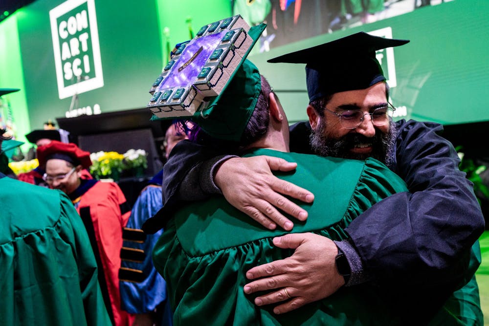 A Communication Arts and Sciences professor hugs a graduate before they receive their diploma during the Michigan State University College of Communication Arts and Sciences graduation ceremony at the Breslin Student Events Center on Michigan State University’s campus in East Lansing, Mich., on Friday, May 1, 2026.
