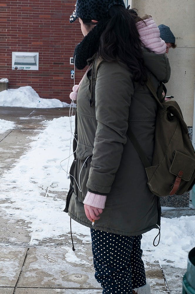 <p>Finance junior Michelle Jing smokes a cigarette Feb 16, 2015, outside of the MSU Library. Michelle is an international student and says a tobacco ban on campus will create more exclusivity for international students. Hannah Levy/The State News</p>