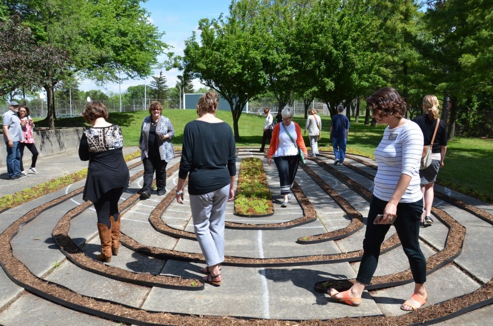 <p>East Lansing residents walk through the new meditative labyrinth located at &nbsp;Patriarche Park in East Lansing, unveiled on May 31. The labyrinth was designed and built by MSU alumnus Kenneth Hunter.&nbsp;</p>