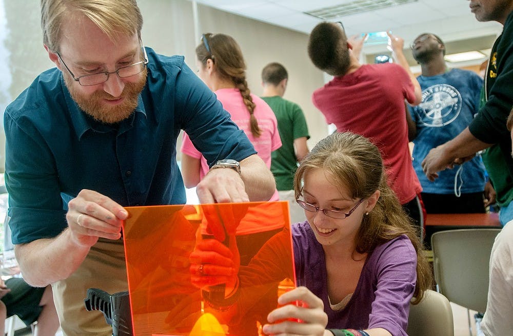 	<p><span class="caps">MSU</span> professor Richard Lunt, left, and Battle Creek, Mich., resident Allison Hamner, 16, shine a flashlight through a piece of colored plastic July 23, 2013, during the Introduction to Robotics Engineering at the Engineering Building. The two were trying power a solar-powered toy car. Weston Brooks/The State News</p>